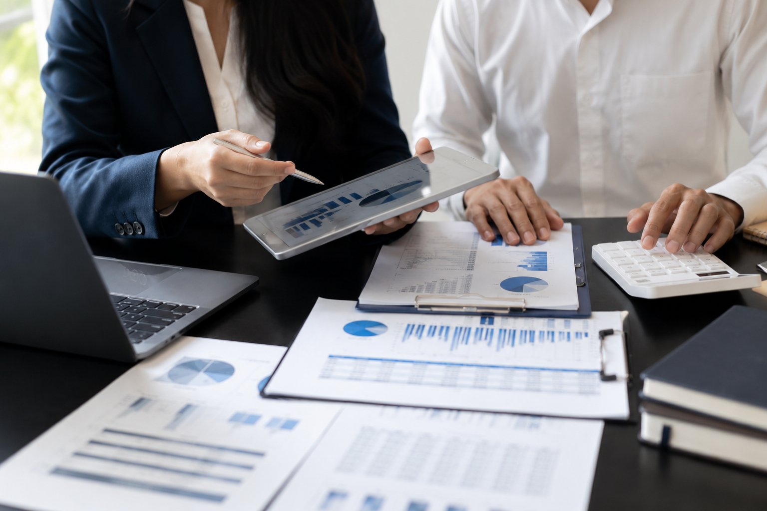 Finance professionals reviewing financial charts and reports with a laptop and calculator